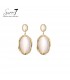 Beige oorbellen met een goudkleurige rand en een cat eye steen